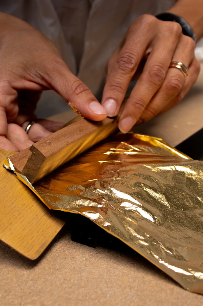 Operator hand-painting a frame with gold finish