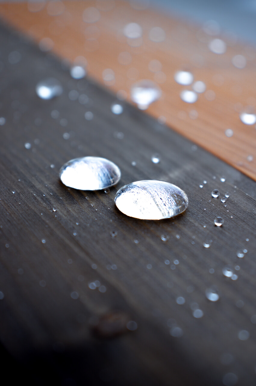 Gocce d'acqua su una tavola di legno resa impermeabile da un impregnante per legno
